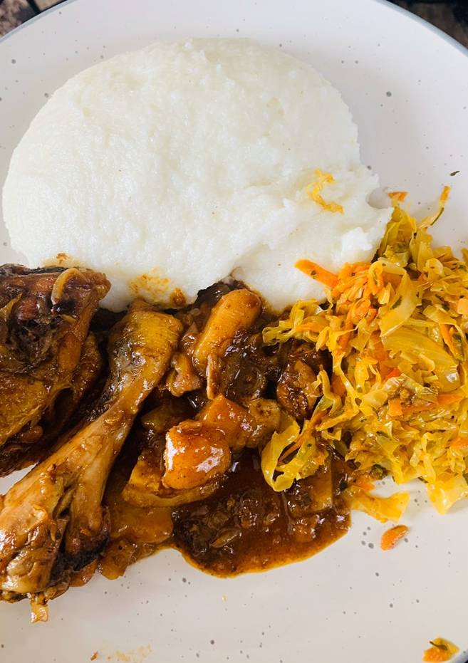 A plate of soft pap served with a saucy chicken stew and cabbage